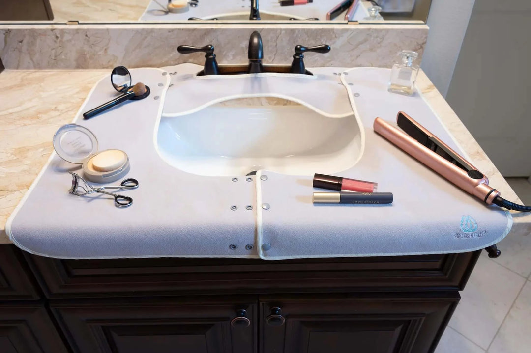 Makeup, Hot Tools and Perfume lying on Top of a Grey Splashpad Sink Mat - Splash Guard for Bathroom Sink